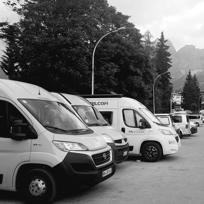 a black and white photo of a parking lot full of vans